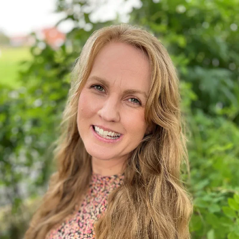 Elin Sjöqvist, författare till böckerna om Daisy & Diego, fotograferad utomhus framför grönska.